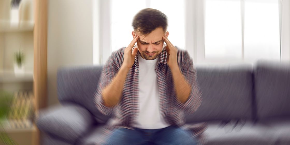 Man holding his head with blurry surroundings 