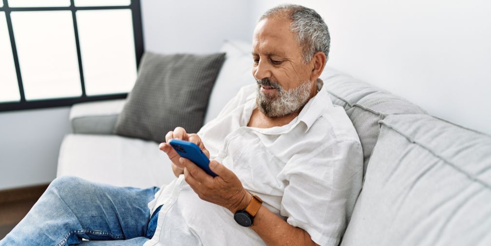 man sitting on a couch looking at his phone 
